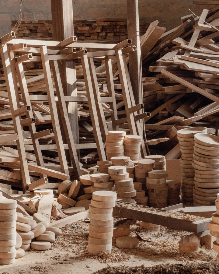 Stacked timber, frames and turned wooden discs on the Mâzia workshop floor